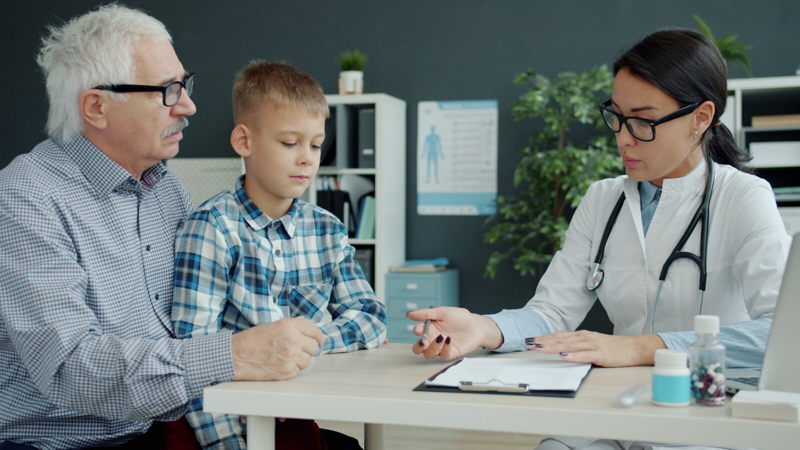 Doctor consults with grandfather and grandson in office